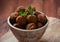 Falafel balls with parsley in wooden bowl with tahini sauce.