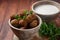 Falafel balls with parsley in wooden bowl with tahini sauce.