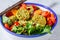 Falafel salad with baked vegetables and tomatoes in white bowl. Israeli street food concept