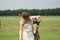 A falcon color foal in the field, wearing a fly mask, young woman takes off the fly mask