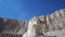 Falcon horus statue in front of Mortuary Temple of Hatshepsut in Luxor Egypt low angle sky and cliff