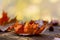 Fall background. Orange yellow autumn leaves on wooden table. Sunny blurred background, bokeh lights