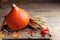 Fall background with pumpkin decorated with leaves, wheat and rowan on rustic wooden table. Autumn harvest.