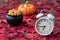 Fall color in red maple leaves on a rustic wood floor with a white analog alarm clock, black cauldron with candy corn, and a ceram
