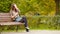 Fall concept - beautiful woman drinking coffee in autumn park under fall foliage