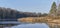 Fall country landscape with thin crust of ice on water surface, heron on riverbank, scenic forest