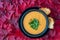 Fall harvest bisque soup of pureed squash and other fall vegetables, in a black bowl and plate, toasted bread, basil, background o