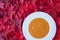 Fall harvest bisque soup of pureed squash and other fall vegetables, in a white bowl, on a background of red maple leaves