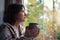 Fall melancholy mood concept. Sadness depressed woman sitting near window and looking at autumn landscape outside in rainy day