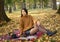 Fall picnic on october. Young woman with black hair resting in nature on blanket and smiling. Autumn mood. People