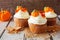 Fall pumpkin spice cupcakes with creamy frosting close up against rustic wood