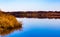 Fall reflections; when the leaves fall, you see a lot more on the shoreline. The tree branches, houses, roads, sheds are visible.