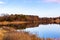 Fall reflections; when the leaves fall, you see a lot more on the shoreline. The tree branches, houses, roads, sheds are visible.