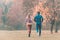 Fall running in a park, seen from behind couple