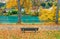 Fall scenery of an empty wooden bench by the bank of turquoise Lech River