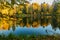 Fall season start idyllic lake reflections of fall foliage. Colorful autumn foliage casts its reflection on the calm waters