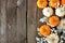 Fall side border of orange and white pumpkins and silver autumn leaves against a dark wood background