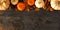 Fall top border banner of pumpkins and autumn decor on a dark stone background