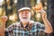 Fallen autumn leaves strewn about the ground. Elderly man smiling outdoors in nature. Grandfather having fun in autumn