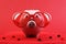 Fallen in love piggy bank with red heart sunglasses standing on red sand with red shining heart glitters in front of red