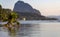 Fallen palm tree in tropical harbor in evening with big mountain on horizon. Sunset in lagoon in Philippines, Palawan, El Nido.