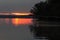 Fallen tree pointing to early morning red sunrise on Rend Lake, Illinois