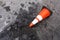 fallen white black orange striped traffic cone with broken weathered street backtop