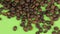 Falling coffee beans on a rotating green screen, isolated.