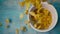 Falling cornflakes and the bowl on blue wooden table, super slow motion