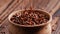 Falling flax seeds, linseed in wooden bowl on dark background close up