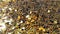 Falling gold glitter foil confetti, super slow motion movement on golden background, holiday and festive fun