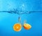 Falling of orange halves into water on color background