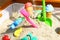 Falling sand in the Sandbox. Various toys in different colors. C