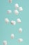 Falling slices of white marshmallows on a light background. Texture for design. Freeze in motion