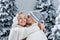 Falling snow and kisses. Happy young couple close-up hugs and kiss near christmas trees at the eve of new year