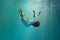 Falling into unknown. Surreal underwater creative scene featuring elegant young woman levitating gracefully underwater