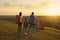 Families with a child tourists with backpacks admiring the sunset on a camping adventure in nature