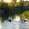 Families of friends canoe down the river at sunset. Cheerful company of tourists