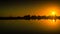 Families walk and play on the beach at sunset, reflected in the still water of the lagoon.