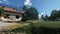 Family around green house with solar panels and wind turbine near lake and forest, 4K