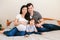 Family Asian Chinese pregnant woman and Caucasian man with mixed race toddler girl sitting on bed at home. Mother, father, baby