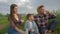 Family atmosphere, merry girl with guy and kid boy pour milk into glasses and drink during family picnic and enjoy