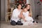 A family with a baby sits sitting near the Christmas tree