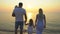 Family beach sun sunset. Happy family of four holding hands standing on dreamy sandy beach watching ocean at golden