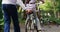 Family, bike and a girl learning to ride in a park with the hand of a grandparent closeup outdoor for development. Back