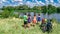 Family on bikes cycling outdoors, active parents and kids on bicycles, aerial top view of happy family with children near river