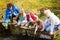 Family On Bridge Fishing In Pond With Net