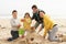 Family Building Sandcastle On Winter Beach