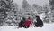 Family building a snowman in park, lovely child fixing buttons, snowed trees, beautiful winter family portrait, real teamwork