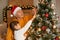 Family celebrating Christmas, grandpa and child girl with pigtails decorating Christmas tree, female king in white sweater and